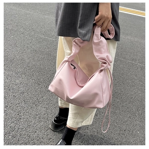 Close-up of pink pleated shoulder bag with scrunchie style strap and smooth zipper closure