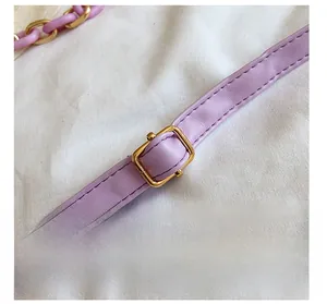 Detail view of purple leather shoulder strap with gold metal buckle and stitching