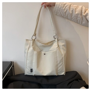 Detailed macro view of cream-colored nylon tote bag featuring front snap pocket design