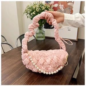 Close-up of pink pleated handbag with quilted texture and decorative white pearl strap