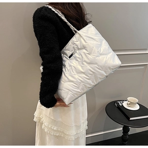 Silver quilted tote bag with metallic finish and woven handles shown with fashion outfit
