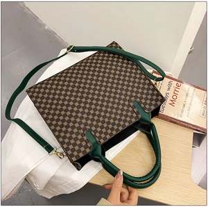 Detail of vintage tote bag showing retro patterns, green leather straps, and gold hardware