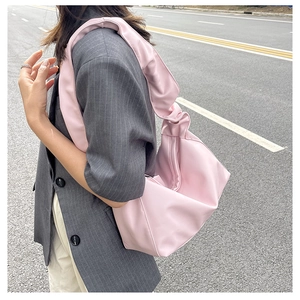 Detail of light pink ruched tote bag with smooth satin texture and wide pleated shoulder strap