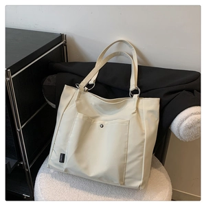 Detail of off-white nylon tote bag with front pocket and branded side label
