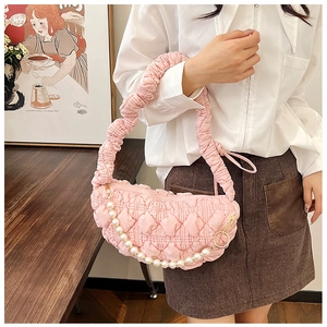 Detailed shot of a pink pleated underarm bag with a pearl strap and quilted heart patterns