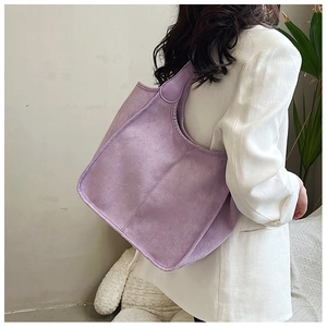 Detailed view of lavender purple suede tote bag with wide shoulder strap on model