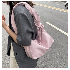 Detail view of the soft pleated texture and light pink faux leather of the baguette bag