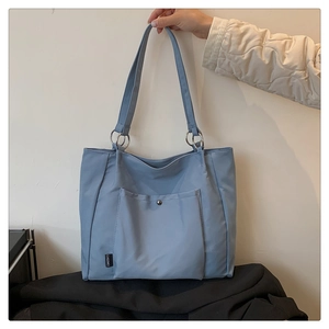 Detail showing the light blue nylon tote bag with a metal snap pocket and brand label