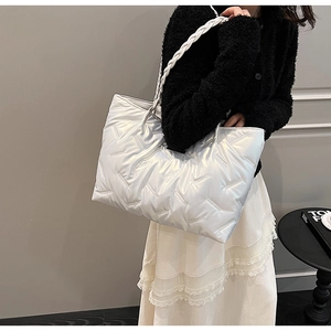 Detail of silver quilted tote bag with white braided handles on a stylish model