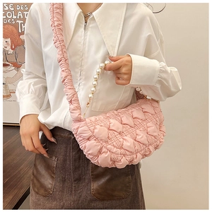 Detail of pink puffy quilted bag featuring pearl handle and pleated shoulder strap