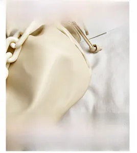 Détail du sac nuage beige avec cuir souple plissé et une grosse chaîne en résine blanche
