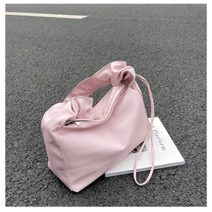 Close-up of soft pink pleated leather baguette bag with a stylish cloud shape design