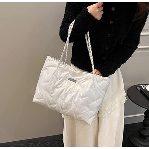Detail of pearl white quilted tote bag with woven rope handles and V-shaped stitching