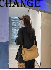 Détail du sac bandoulière en toile jaune moutarde avec poche latérale et bouton noir