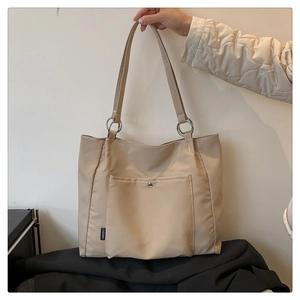 Detail of beige nylon tote bag with silver metal ring connector and snap pocket