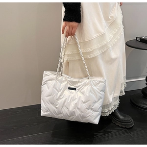 Close-up of white puffer tote bag with quilted pattern and stylish woven rope handle