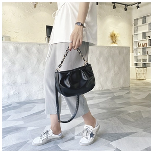 Detail of black pleated cloud bag with gold chain strap and detachable crossbody shoulder strap