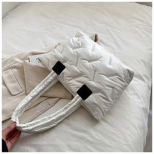 Macro detail of white quilted nylon tote bag featuring V-shaped stitching and black patches