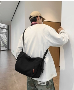 Détail de la sacoche en toile noire arborant une étiquette de marque orange élégante