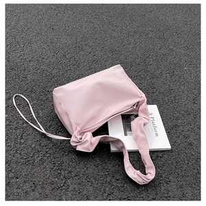 Close-up of pink ruched baguette bag with pleated handle on asphalt background