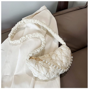 Detail of quilted cloud bag in off-white with pearl chain on a white suit