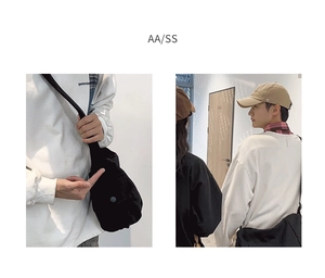 Gros plan d'un sac bandoulière en toile noire avec un sweat-shirt blanc surdimensionné