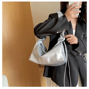 Detail of silver metallic hobo bag featuring a stylish knotted shoulder strap design