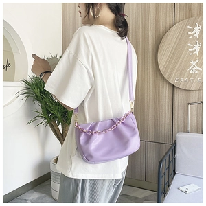 Detailed view of purple ruched cloud bag with leather strap and decorative gold chain