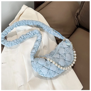 Detail of light blue quilted cloud bag with pearl chain and ruched strap on a white blazer