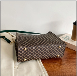 Detail view of tote bag with vintage brown monogram pattern and protective gold metal feet