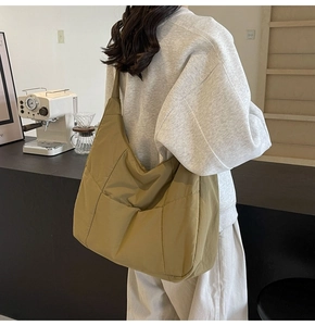 Detailed side view of a large olive green quilted nylon tote bag with utility pockets