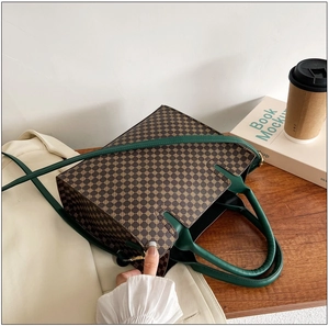 Detail of vintage printed tote bag with brown geometric pattern and green leather handle