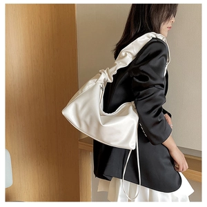 Detailed view of the white hobo bag showing the elegant ruffled shoulder strap design