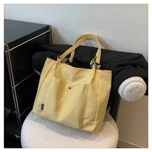 Detail of yellow nylon tote bag featuring front snap pocket and silver metal buckle