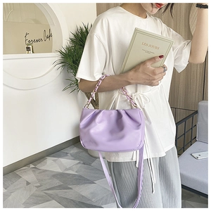 Detail of lavender ruched cloud bag featuring an acrylic chain and soft leather texture
