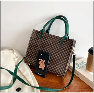 Detailed view of vintage pattern tote bag with dark green handles on wooden table