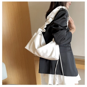 Detail of white baguette bag showing the unique gathered cloud-style shoulder strap design