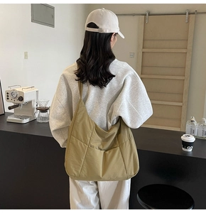 Detail view of olive green quilted nylon tote bag worn by model in a modern cafe