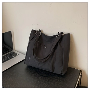Close-up of black nylon tote bag with silver metal ring straps and front button pocket