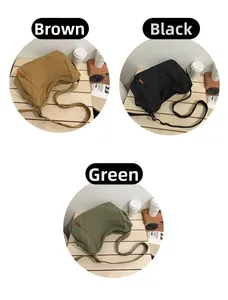 Trois sacs bandoulière en toile en marron, noir et vert sur une table en bois