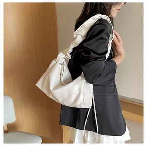 Close-up of a white ruched cloud bag featuring a soft leather texture and stylish shoulder strap
