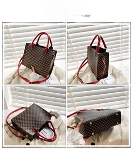 Detail view of large checkered tote bag with red leather trim and gold metal feet studs