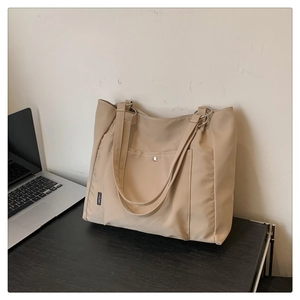 Detail of a large beige tote bag on a desk next to a laptop for office use