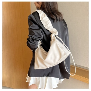 Detail of white pleated shoulder strap on textured leather baguette bag for women