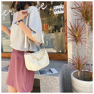 Detail showing beige ruched cloud bag with thick chain strap and soft leather texture