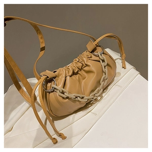 Détail du sac nuage camel avec texture plissée et chaîne en résine sur un blazer blanc