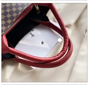 Detailed close-up of a stylish red leather handle and gold zipper on a tote bag