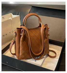 Brown lychee leather bucket bag with quilted details presented in a premium black gift box