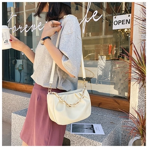 Detail of off-white pleated croissant bag with chunky gold chain strap and soft leather finish