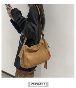 Détail latéral du sac bandoulière en toile marron avec poche et étiquette orange